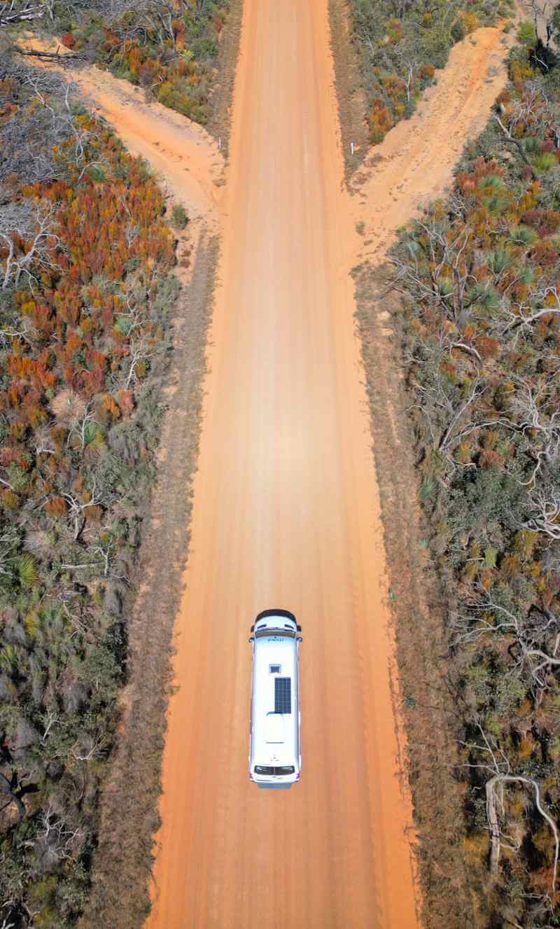 ): Biały kamper na czerwonej ziemi w Australii podczas słonecznego dnia.