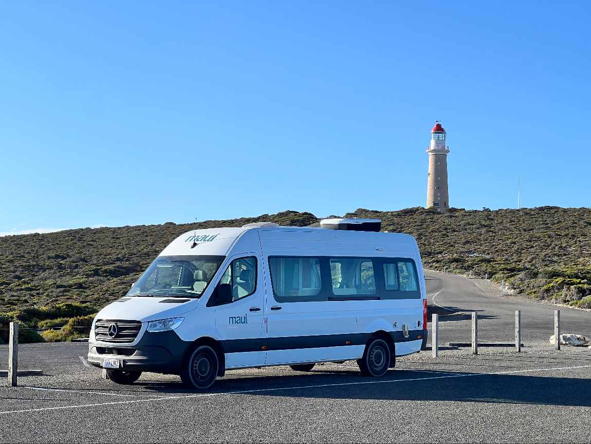 Biały kamper na parkingu w Nowej Zelandii z widokiem – zestawienie cen wynajmu w NZD