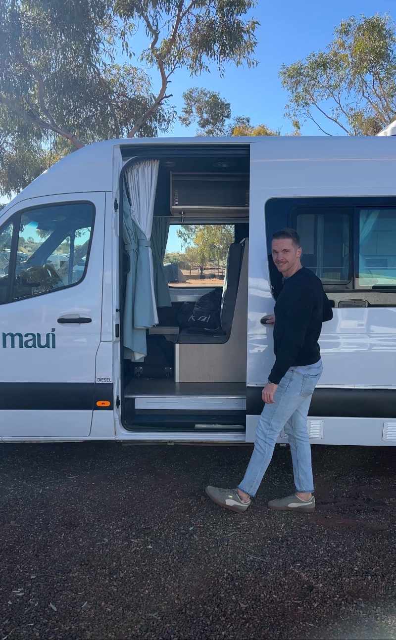 omfortowy kamper dla 2 osób zaparkowany na kempingi niedaleko Uluru podczas zachodu słońca – idealny model dla par na road trip po Czerwonym Sercu Australii.