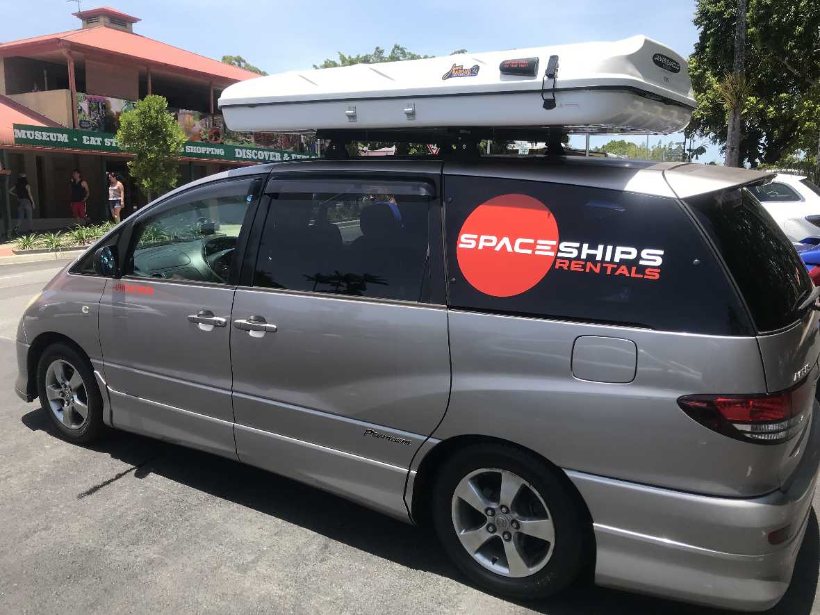 Kompaktowy minivan w wersji kamper z rozłożonym namiotem dachowym, wyposażony w system sypialny i aneks kuchenny, idealny na trasy po Australii.