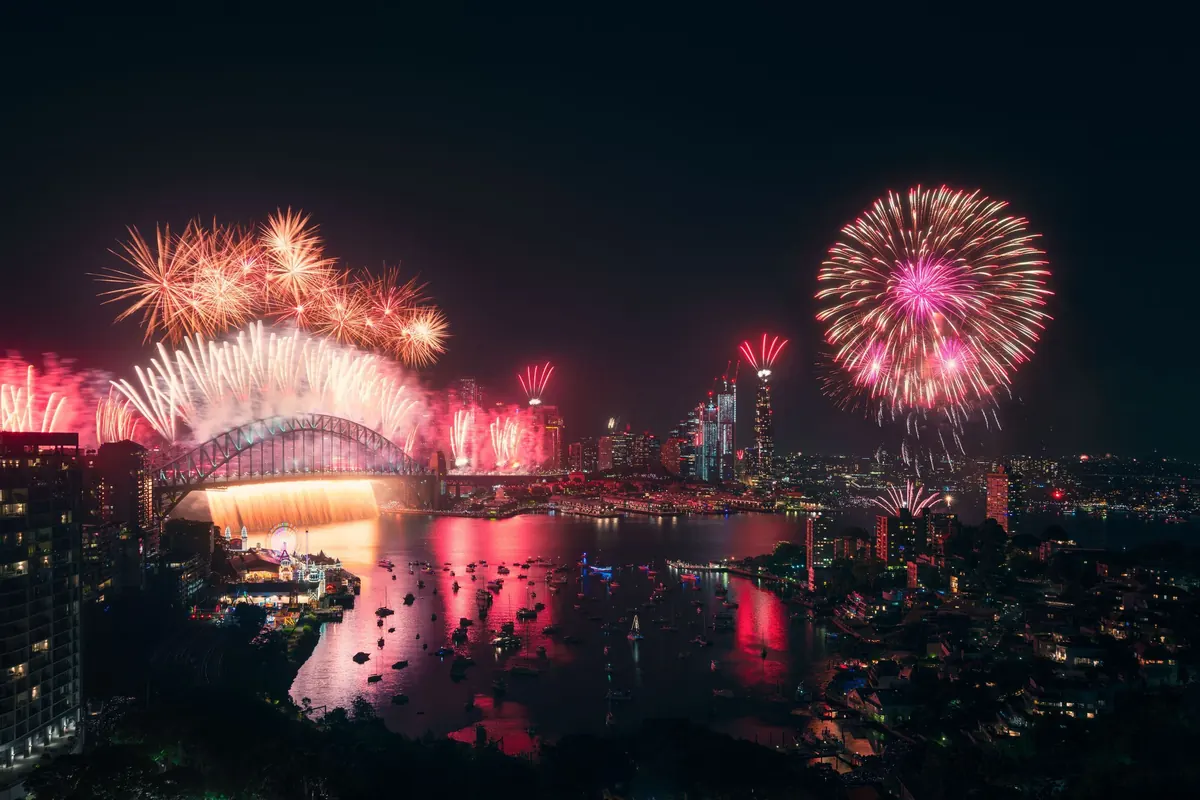 Fajerwerki nad Harbour Bridge i centrum Sydney widziane z wysoka z północnego brzegu zatoki, z Luna Park i łodziami