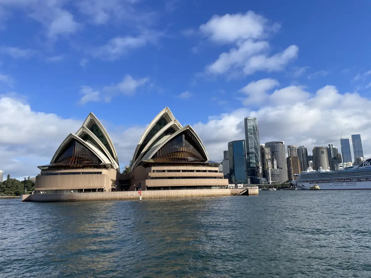 Sydney Opera House widziana od strony zatoki, w tle wieżowce centrum Sydney
